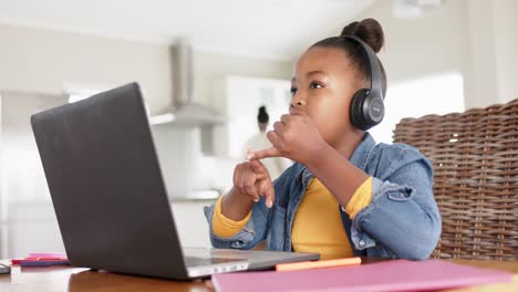 Happy-unaltered-african-american-girl-using-laptop-and-headphones-for-online-lesson,-in-slow-motion