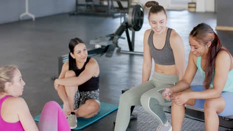 Happy-unaltered-diverse-women-sitting-talking-at-gym-after-group-training-session,-in-slow-motion