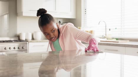 Fröhliches-Afroamerikanisches-Mädchen,-Das-Die-Arbeitsplatte-In-Der-Küche-Reinigt,-In-Zeitlupe