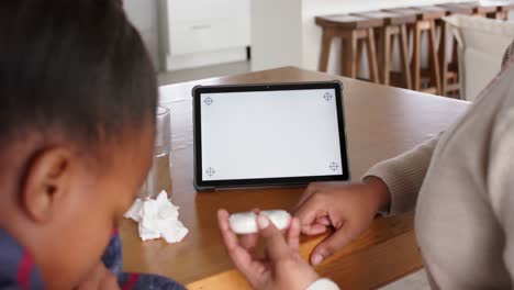 Unaltered-african-american-mother-and-sick-daughter-using-tablet-with-copy-space,-in-slow-motion