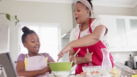 Feliz-Madre-E-Hija-Afroamericanas-Inalteradas-Horneando-En-La-Cocina-Usando-Una-Tableta,-En-Cámara-Lenta