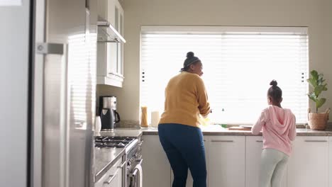 Happy-african-american-mother-and-daughter-washing-up-dishes-in-kitchen,-slow-motion