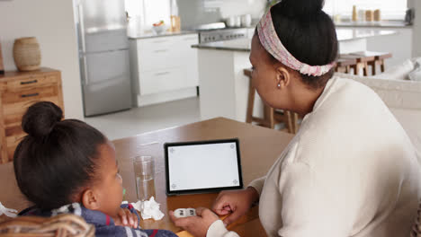 Unaltered-african-american-mother-and-sick-daughter-using-tablet-with-copy-space,-in-slow-motion