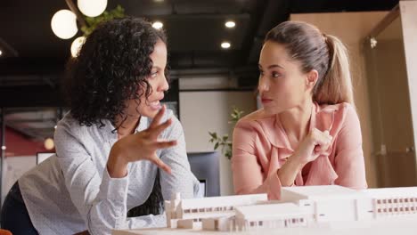 Diverse-female-architects-discussing-architectural-model-of-building-at-work,-in-slow-motion