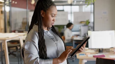 Portrait-of-happy-african-american-casual-businesswoman-using-tablet-smiling-at-office,-slow-motion