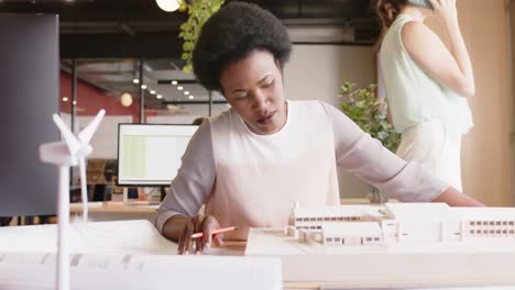 Happy-african-american-female-architect-inspecting-architectural-model-at-work,-in-slow-motion