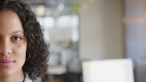 Half-portrait-of-happy-biracial-businesswoman-smiling-at-office,-copy-space,-slow-motion