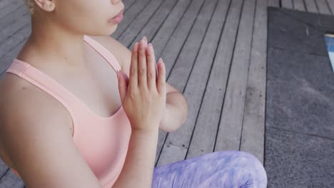 Konzentrierte-Gemischtrassige-Frau,-Die-In-Zeitlupe-Yoga-Praktiziert-Und-Am-Pool-Im-Garten-Meditiert
