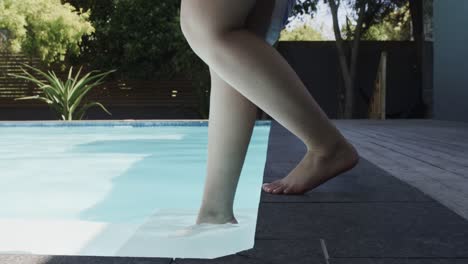 Low-section-of-biracial-woman-walking-in-swimming-pool-in-slow-motion