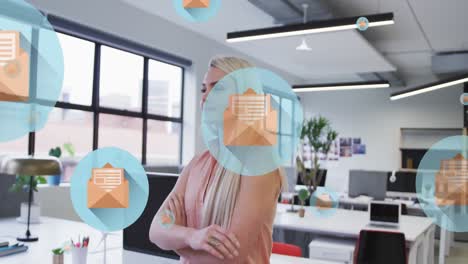 Animation-of-multiple-message-icons-floating-against-caucasian-woman-smiling-at-office
