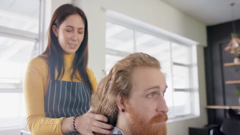Caucasian-female-hairdresser-untying-long-hair-of-male-client-and-advising-at-salon,-in-slow-motion
