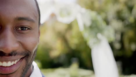Portrait-of-happy-african-american-groom-smiling-at-wedding-in-sunny-garden,-copy-space,-slow-motion
