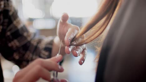 Hands-of-caucasian-male-hairdresser-cutting-ends-of-client's-long-hair-with-scissors,-in-slow-motion