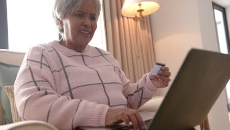 Happy-senior-biracial-woman-using-laptop-for-online-shopping,-unaltered,-in-slow-motion