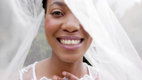 Porträt-Einer-Glücklichen-Afroamerikanischen-Braut-Mit-Weißem-Schleier,-Die-Bei-Ihrer-Hochzeit-Im-Garten-Lächelt,-Zeitlupe
