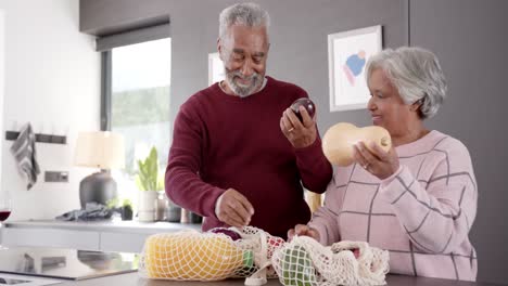 Senior-biracial-couple-unpacking-groceries-in-kitchen,-unaltered,-in-slow-motion