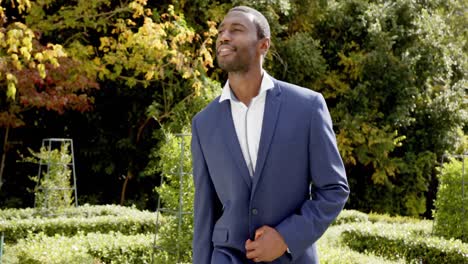 Happy-african-american-groom-walking-and-smiling-at-his-wedding-in-sunny-garden,-slow-motion