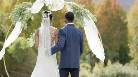 Glückliches-Afroamerikanisches-Paar,-Das-Sich-Bei-Seiner-Hochzeitszeremonie-Im-Sonnigen-Garten-In-Zeitlupe-Umarmt