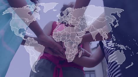 Animation-of-world-map-over-happy-diverse-schoolgirls-stacking-hands-outdoors