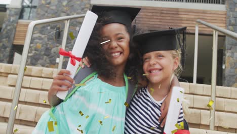 Animation-of-gold-confetti-over-happy-diverse-schoolgirls-with-diplomas-and-mortar-boards-embracing