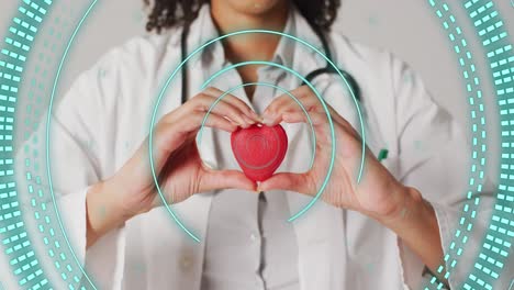 Animation-of-scope-scanning-over-biracial-female-doctor-holding-heart