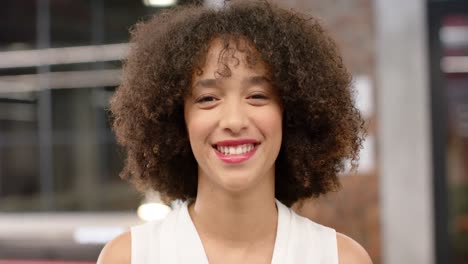 Portrait-of-happy-biracial-creative-businesswoman-smiling-in-office,-in-slow-motion
