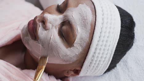 Kosmetikerin-Trägt-Schönheitsmaske-Auf-Das-Gesicht-Einer-Afroamerikanischen-Frau-In-Übergröße-Auf,-Unverändert,-Zeitlupe