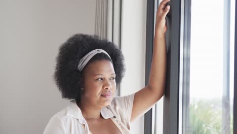 Nachdenkliche-Afroamerikanische-Plus-Size-Frau,-Die-Durch-Das-Fenster-Schaut,-Unverändert,-Zeitlupe
