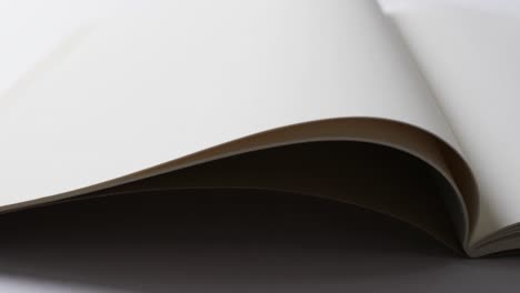 Close-up-of-open-blank-book-with-copy-space-on-white-background-in-slow-motion