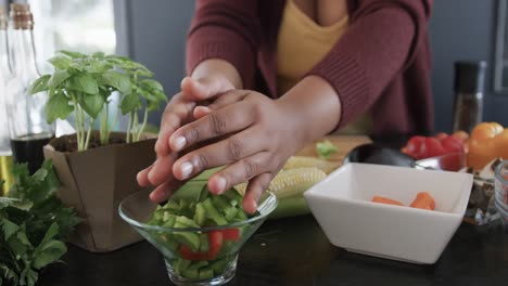 Midsection-of-african-american-plus-size-woman-chopping-vegetables-in-kitchen,-slow-motion