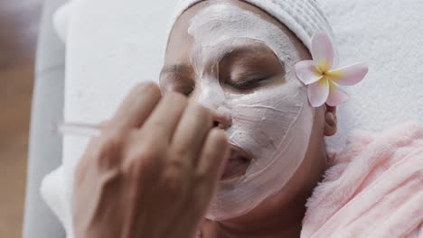 Beautician-applying-beauty-mask-on-face-of-african-american-plus-size-woman,-unaltered,-slow-motion