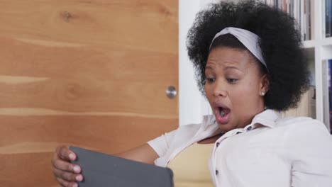 Surprised-african-american-plus-size-woman-using-tablet,-unaltered,-in-slow-motion