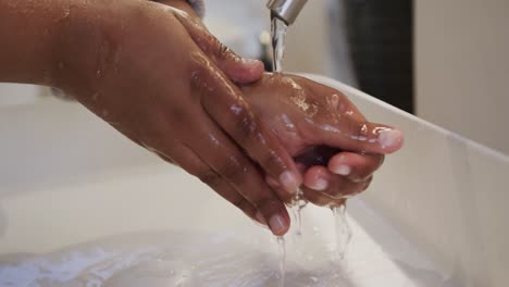 Close-up-african-american-plus-size-woman-washing-hands-in-bathroom,-slow-motion