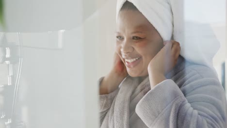 Happy-african-american-plus-size-woman-wearing-towel-on-head-in-bathroom,-unaltered,-slow-motion