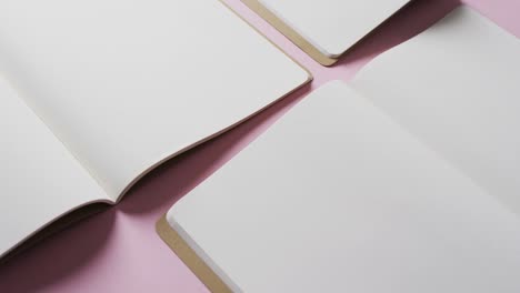 Close-up-of-open-blank-books-with-copy-space-on-pink-background-in-slow-motion