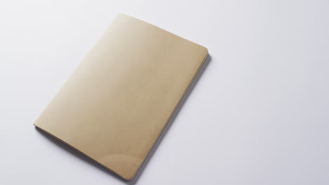 Close-up-of-closed-brown-book-with-copy-space-on-white-background-in-slow-motion