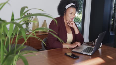 African-american-plus-size-woman-sitting-at-table-and-using-laptop,-unaltered,-slow-motion