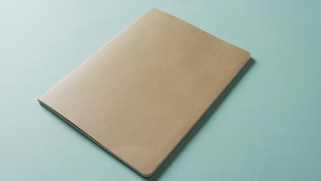 Close-up-of-closed-brown-book-with-copy-space-on-green-background-in-slow-motion