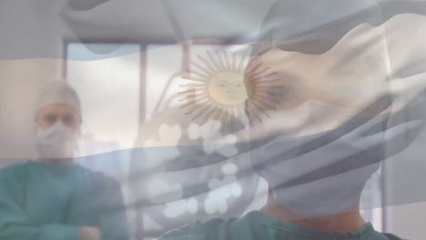 Animation-of-waving-argentina-flag-over-caucasian-male-and-female-surgeons-standing-at-hospital