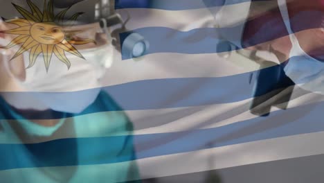 Animation-Der-Uruguay-Flagge-über-Kaukasischen-Männlichen-Und-Weiblichen-Chirurgen,-Die-Operationen-Im-Krankenhaus-Durchführen