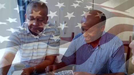 Animation-Der-Schwenkenden-Flagge-Amerikas-über-älteren,-Diversen-Freunden,-Die-Zu-Hause-Karten-Spielen