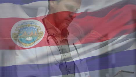 Animation-Der-Costa-Rica-Flagge,-Die-über-Einem-Kaukasischen-Männlichen-Arzt-Winkt,-Der-Im-Krankenhaus-Ein-Digitales-Tablet-Verwendet