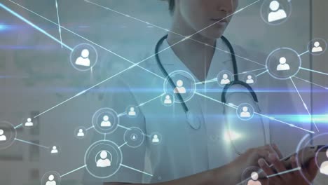 Animation-of-network-of-connections-with-icons-over-caucasian-female-doctor-using-tablet