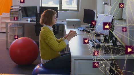 Animation-of-connected-icons-forming-globes,-caucasian-woman-on-exercise-ball-and-using-desktop