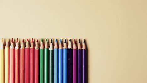 Close-up-of-multi-coloured-pencils-with-copy-space-on-yellow-background