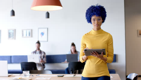 Portrait-of-creative-casual-businesswoman-with-tablet-in-office-with-diverse-colleagues,-slow-motion