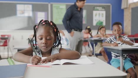 Porträt-Eines-Glücklichen-Afroamerikanischen-Mädchens,-Das-In-Der-Grundschulklasse-Am-Schreibtisch-Schreibt,-Zeitlupe