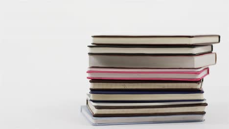 Close-up-of-stack-of-books-on-white-background,-in-slow-motion