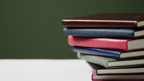 Close-up-of-stack-of-books-on-green-background,-in-slow-motion
