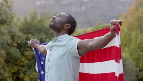 Retrato-De-Un-Hombre-Afroamericano-Sosteniendo-La-Bandera-De-Estados-Unidos-En-El-Jardín,-Cámara-Lenta